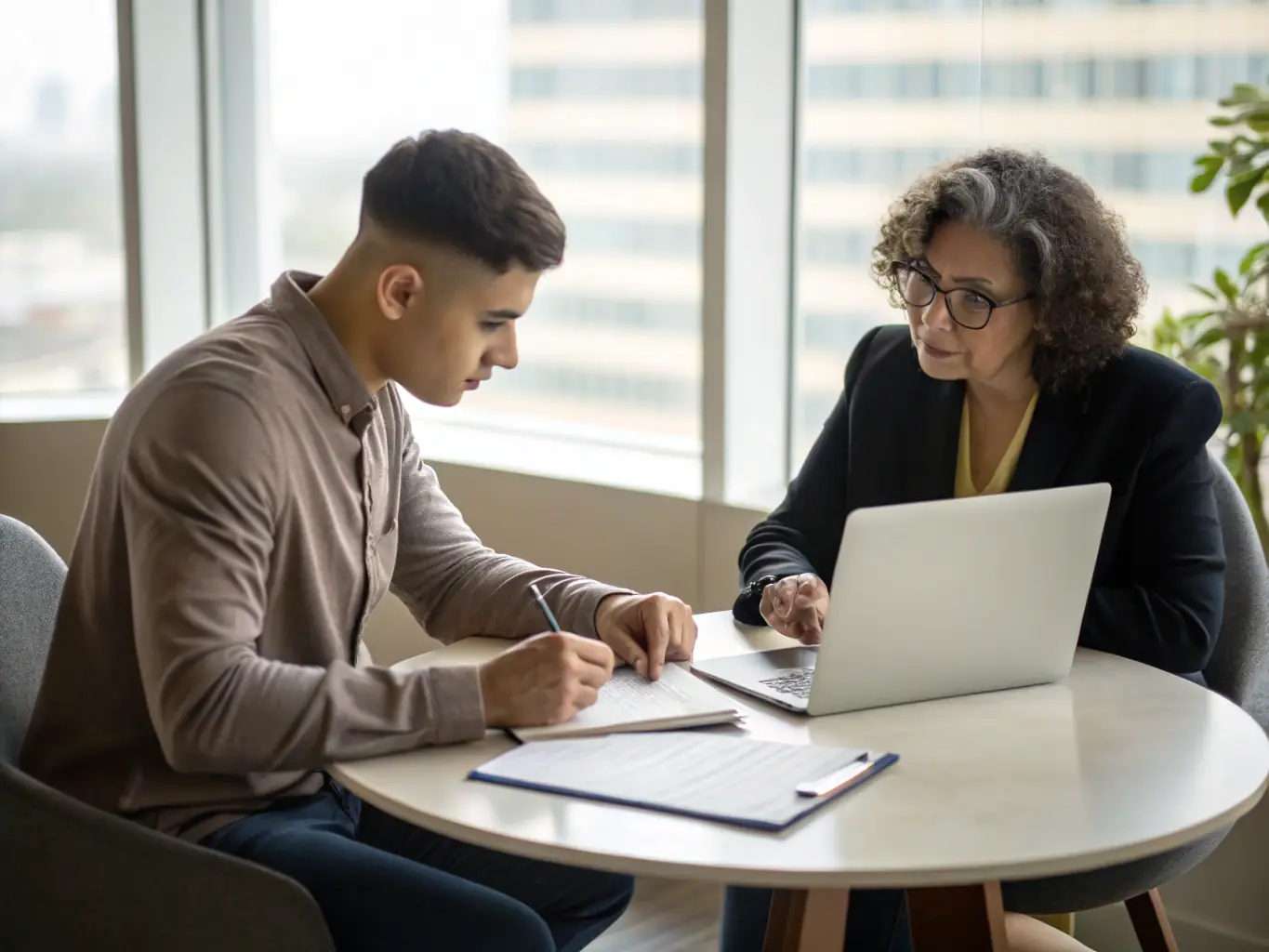 A mentor and mentee engaged in a one-on-one coaching session in a modern office, discussing leadership skills and personal development strategies.